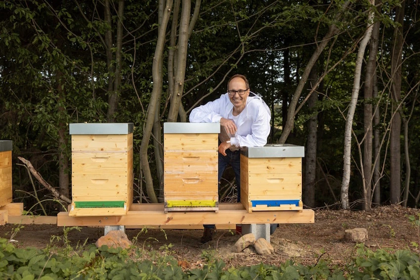 Der Imker Georg Fink steht vor drei Bienenstöcken
